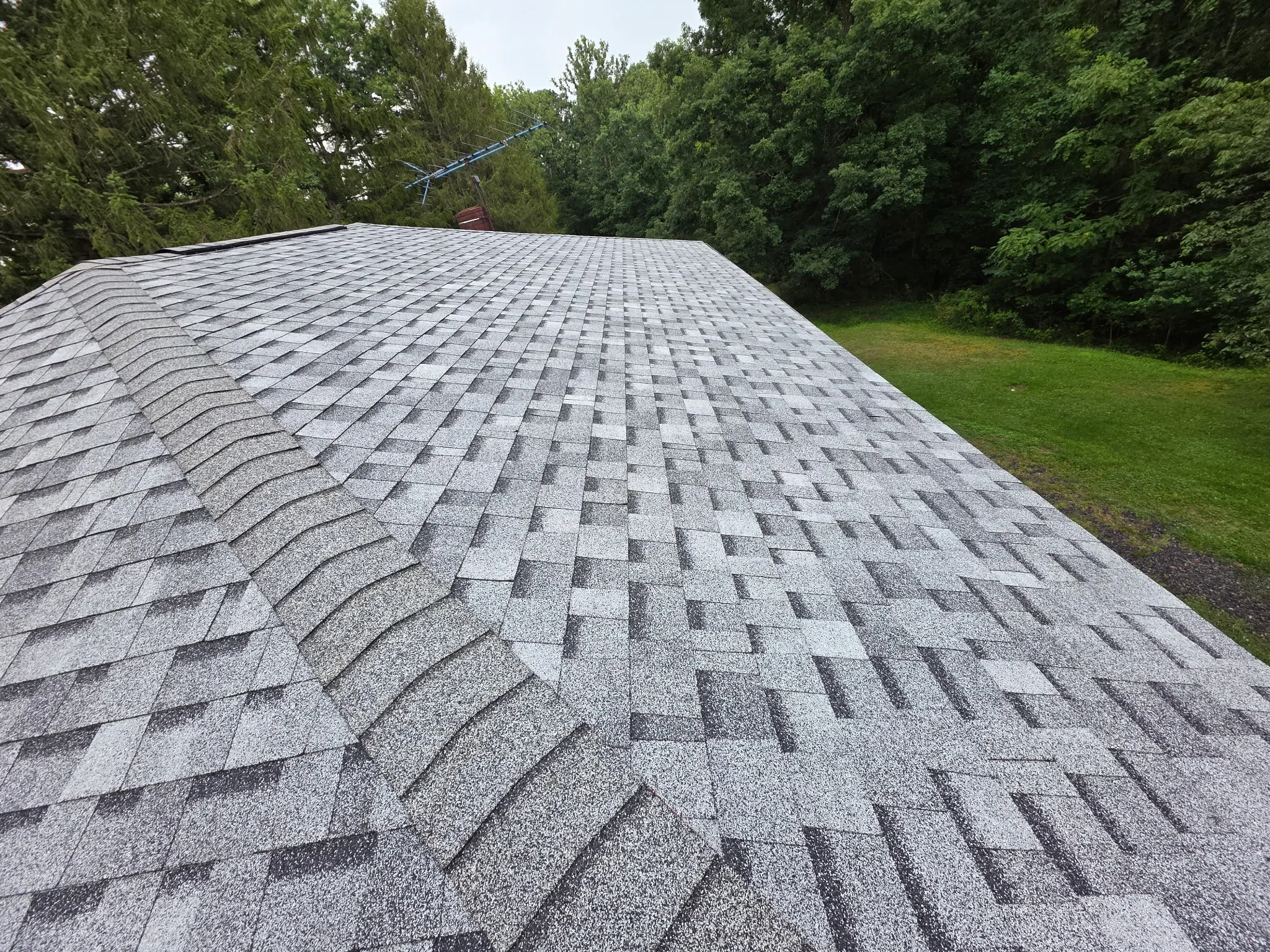 Gray architectural shingles installed on pitched roof with dimensional pattern and ridge vent