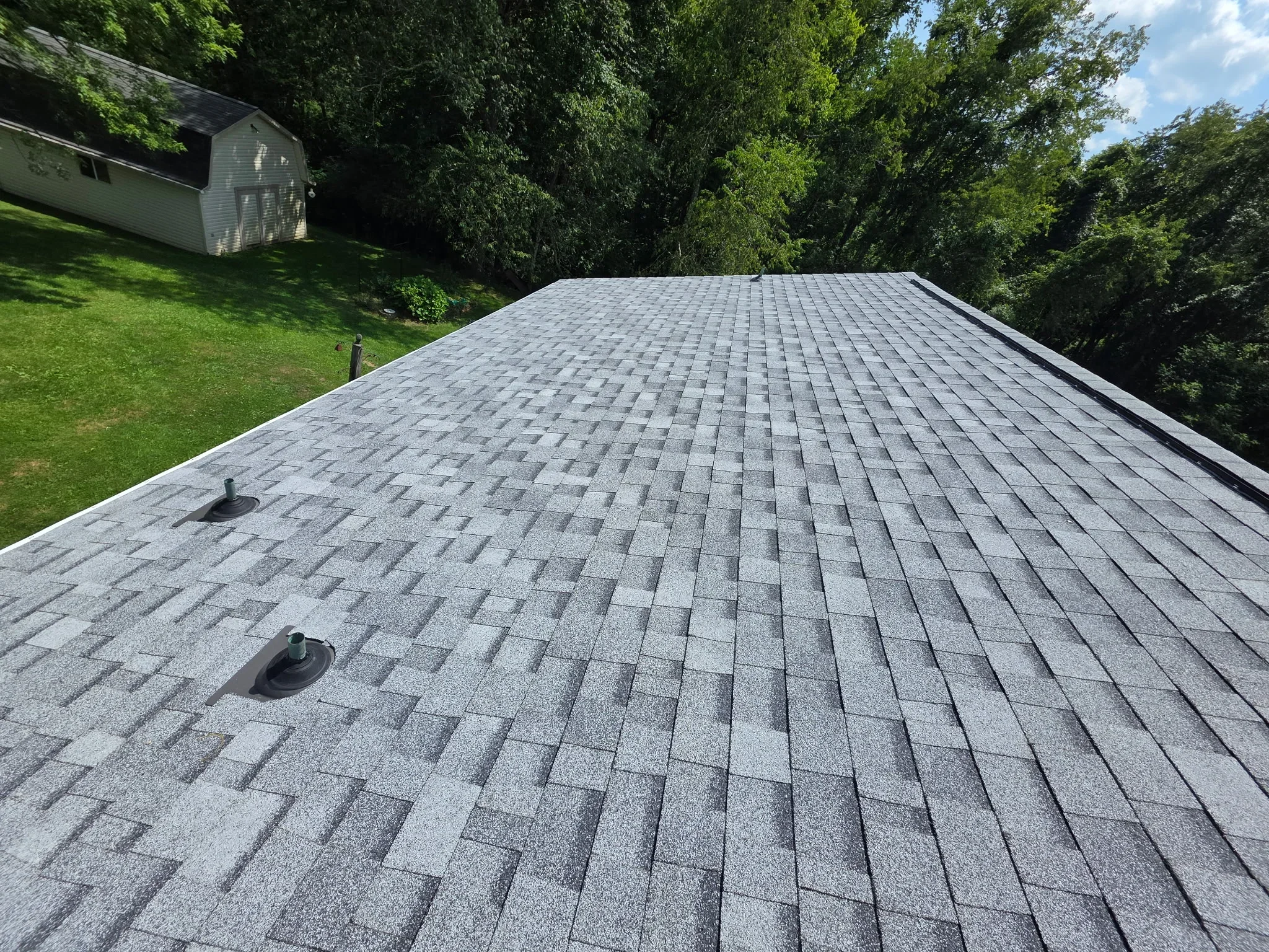 Gray architectural shingles installed in staggered pattern on pitched residential roof with vents