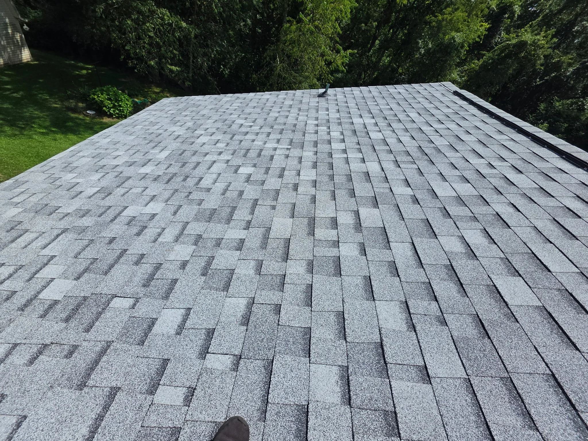 Gray architectural shingles installed in staggered pattern on pitched roof with black trim