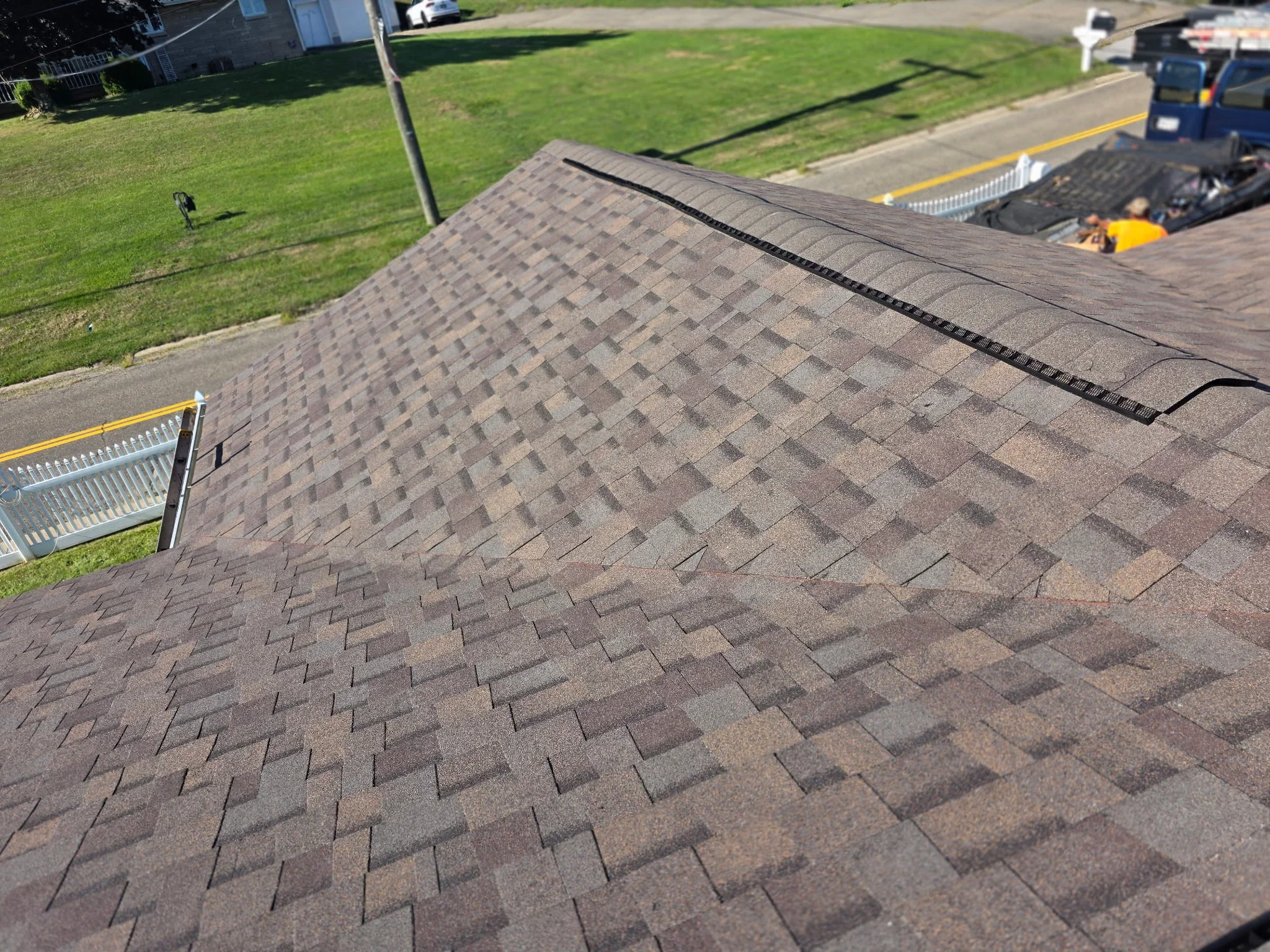 Newly installed gray architectural shingles with ridge cap and gutters on residential roof