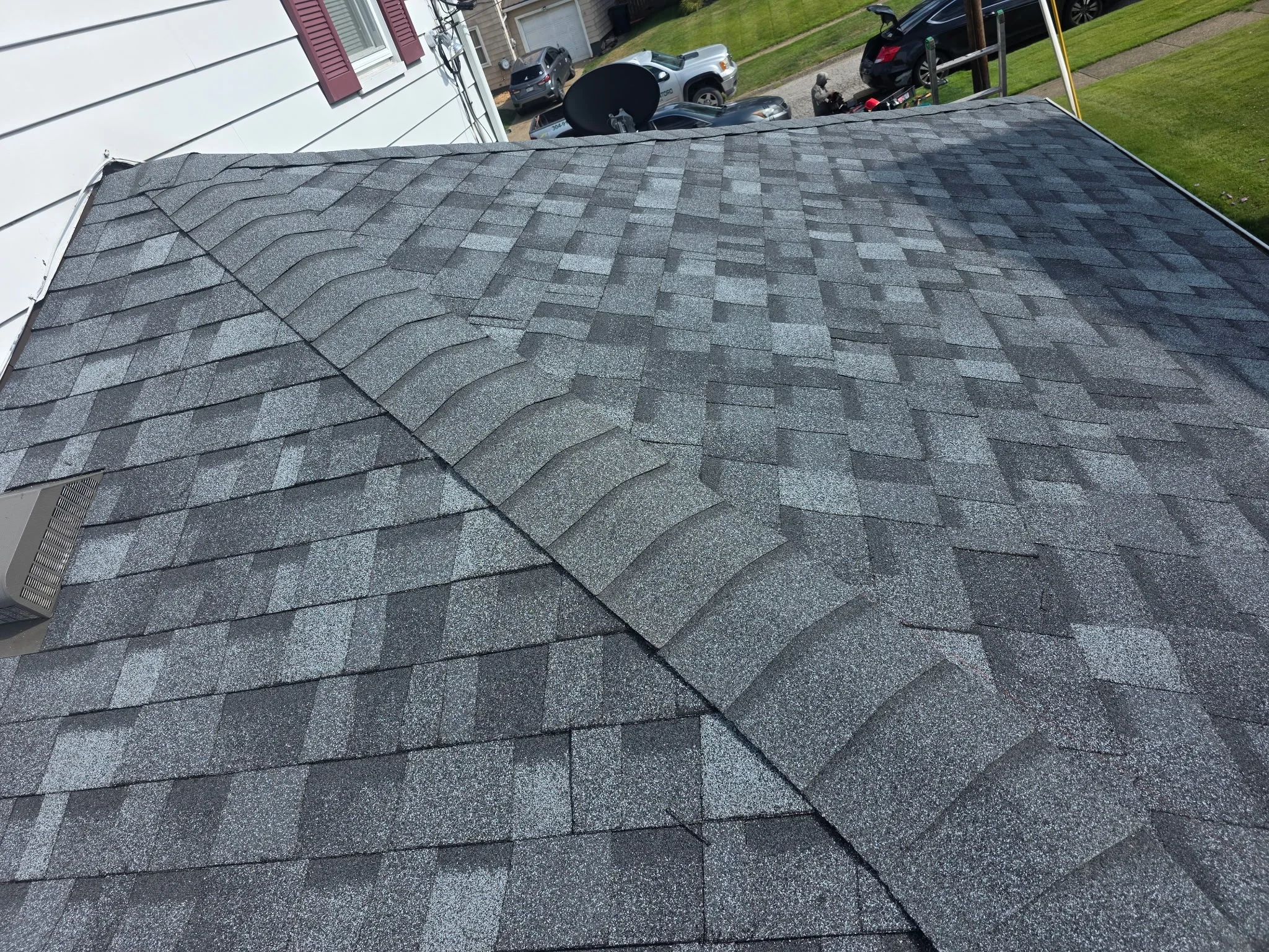 Newly installed charcoal gray architectural shingles with dimensional pattern and proper offset alignment