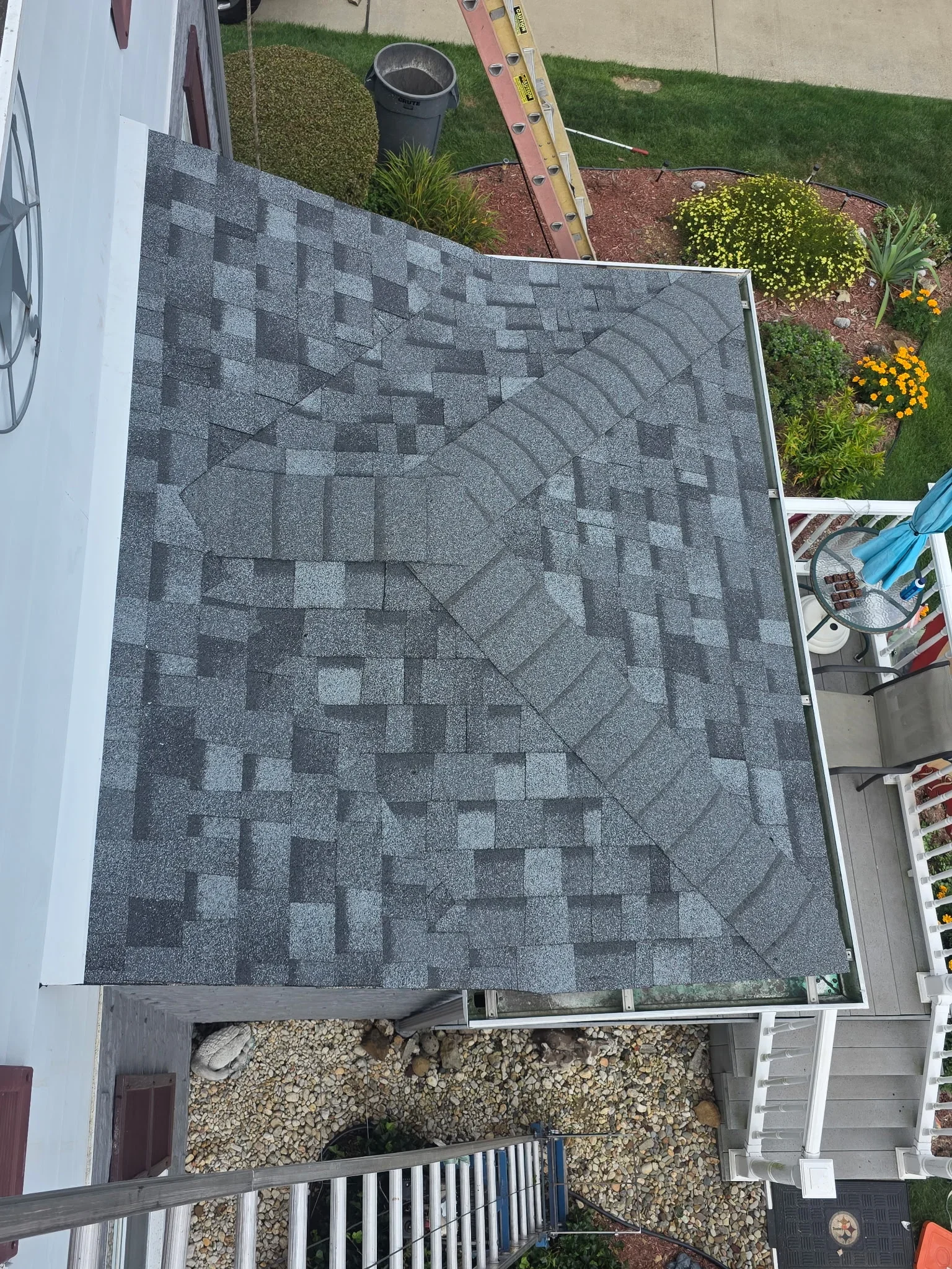 Gray architectural shingles installed in staggered pattern on residential roof with valley flashing