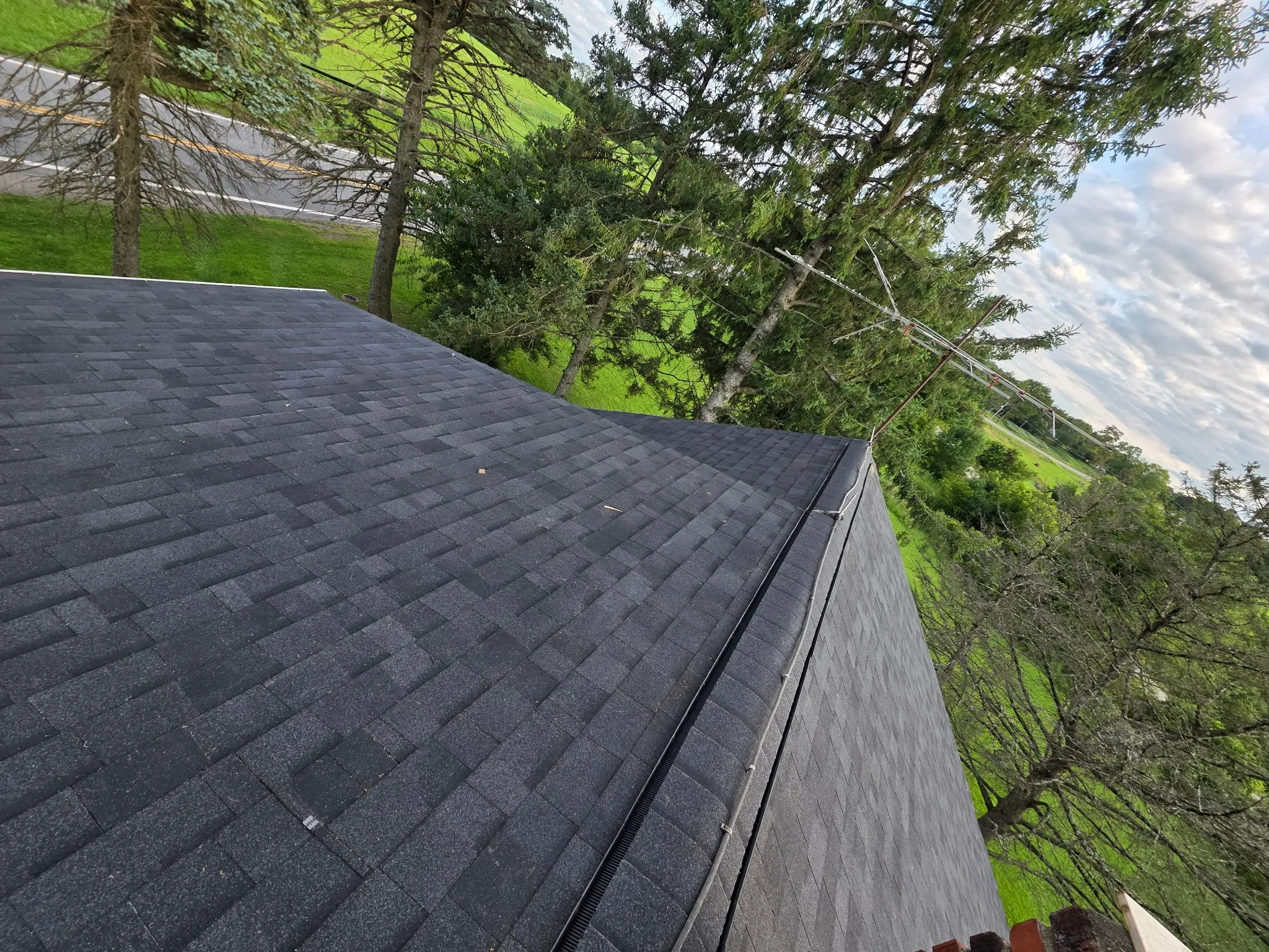 Charcoal architectural shingles with metal gutter on sloped residential roof