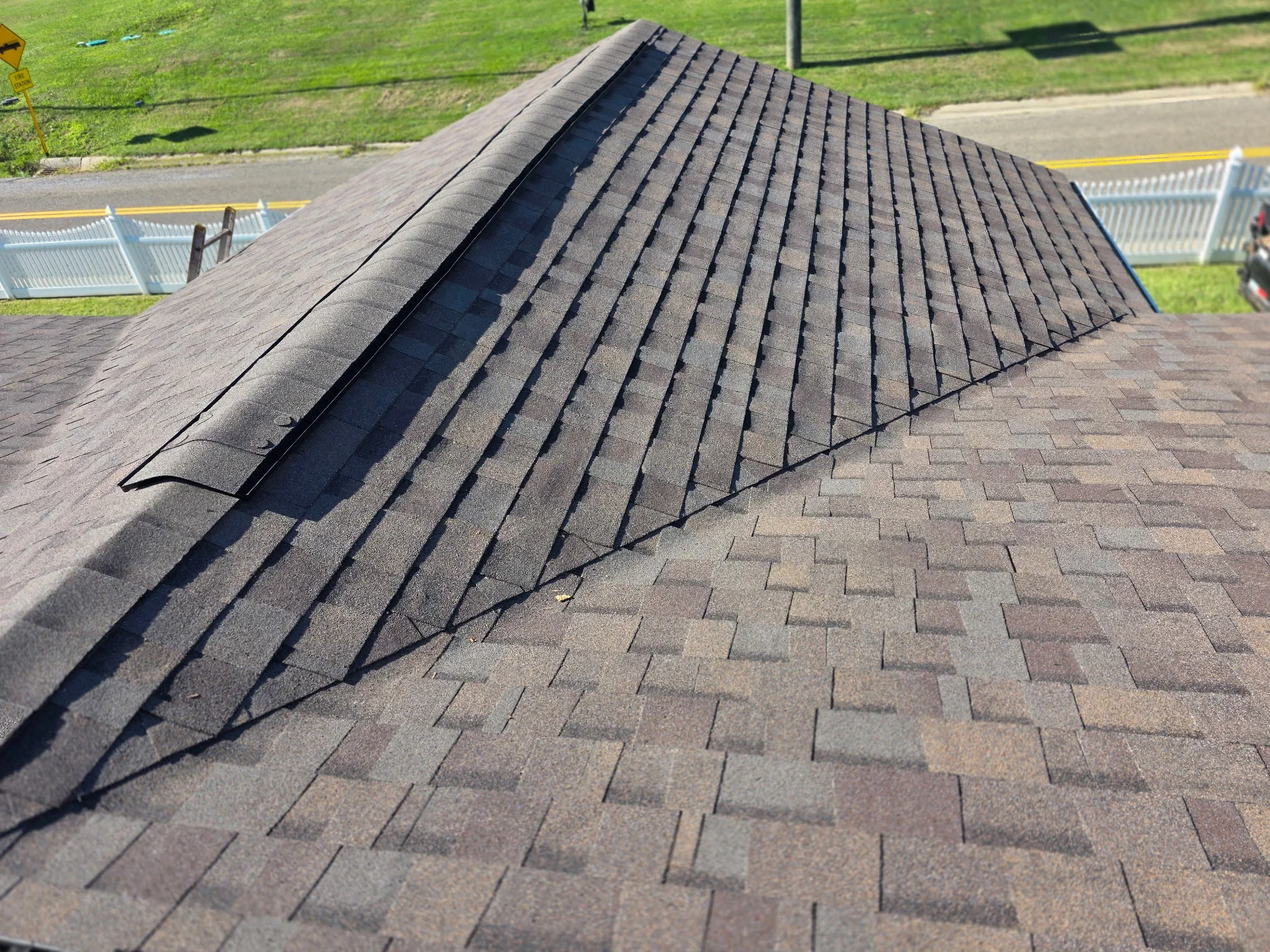 Newly installed architectural shingles with gray tones, ridge cap, and drip edge on residential roof