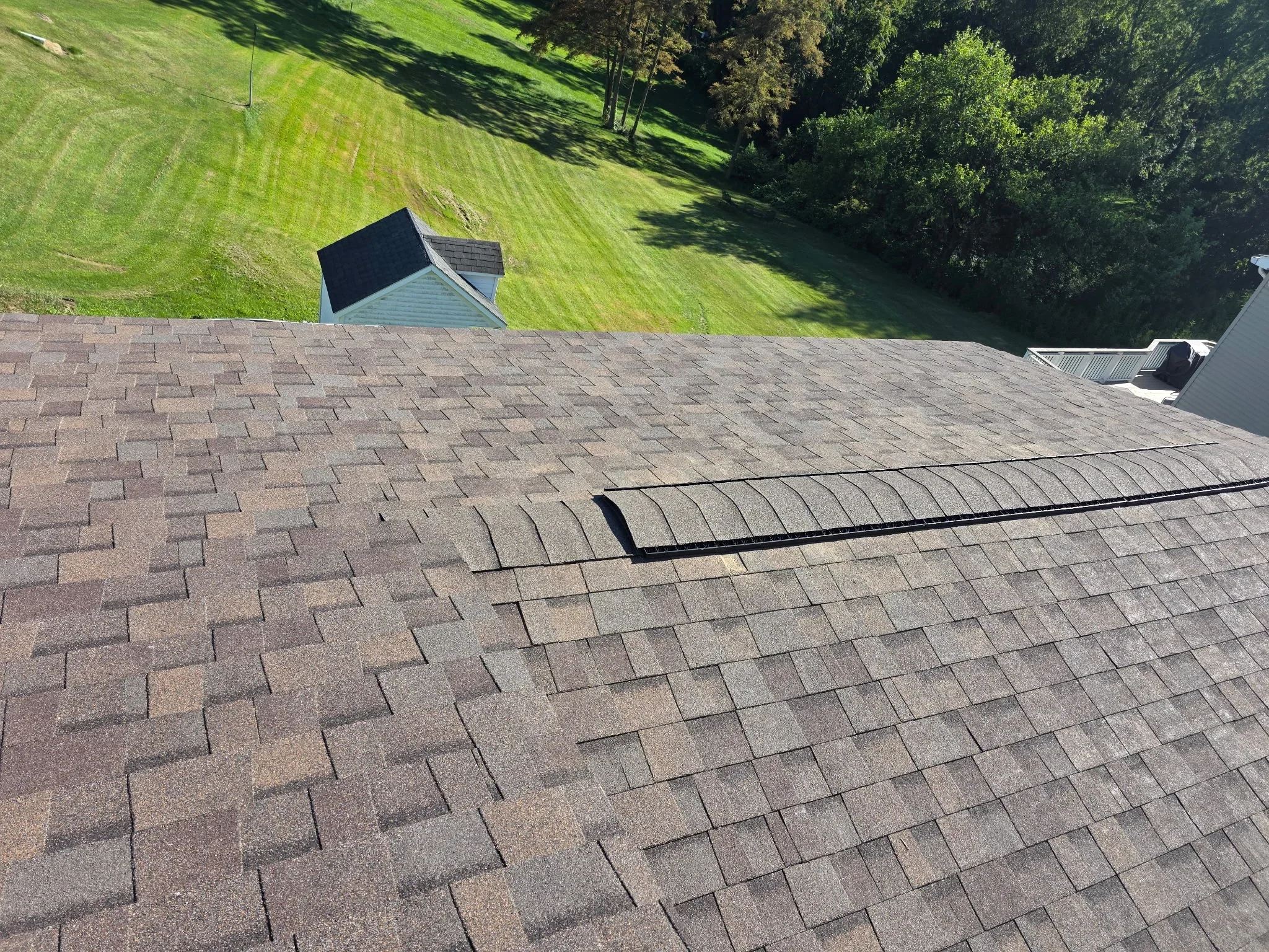 Newly installed architectural shingles in brown and gray blend with metal flashing on sloped roof